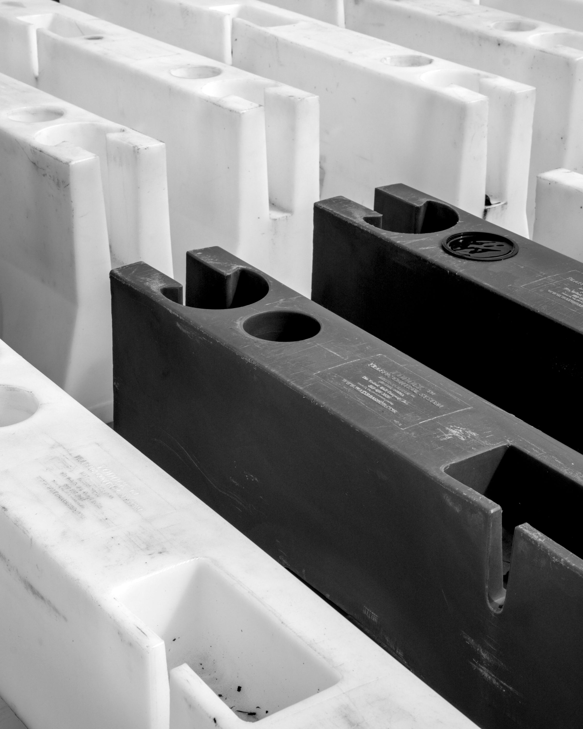Rows of white and dark gray molded plastic barriers with scuffed surfaces, seen from above.