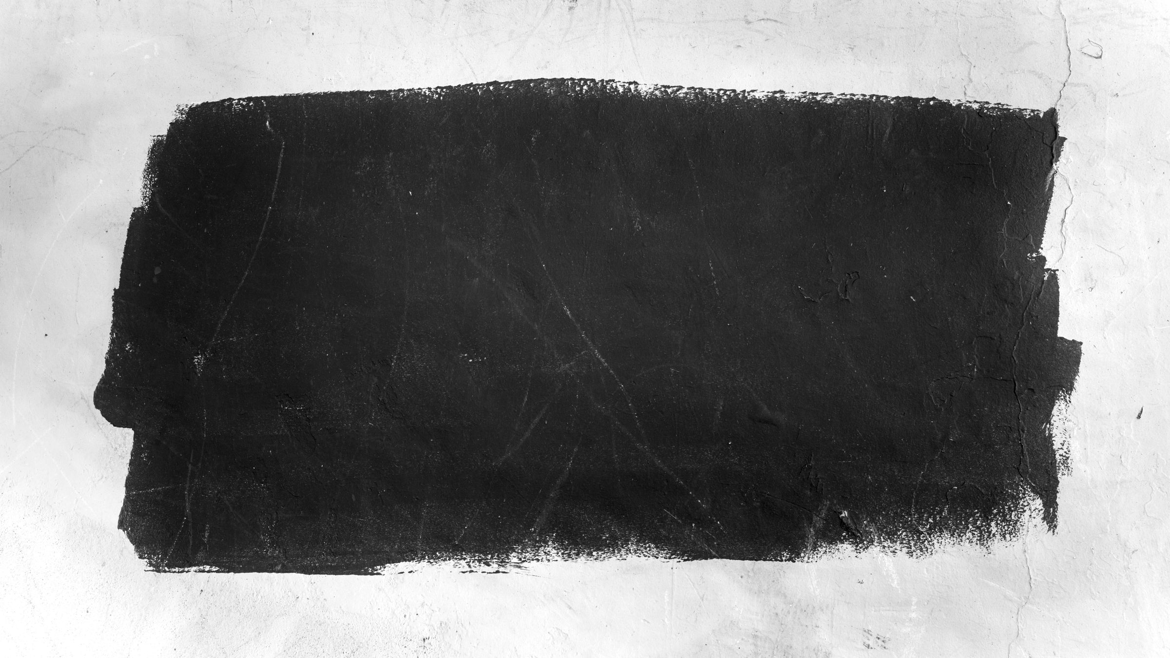 Rough black painted rectangle on a cracked, textured white wall.